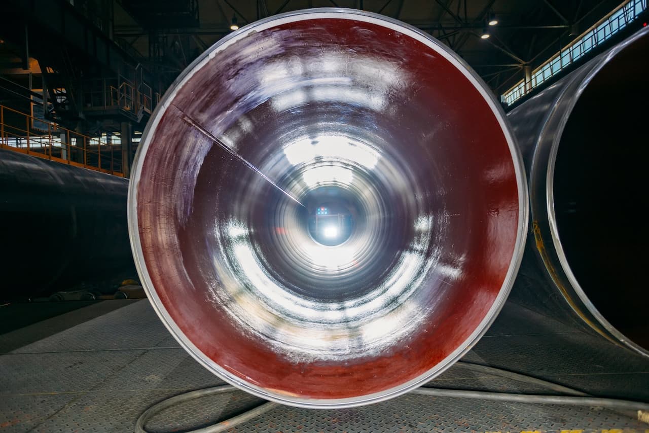 Tubería de acero vista desde su interior, con un acabado brillante y luz al final del túnel.