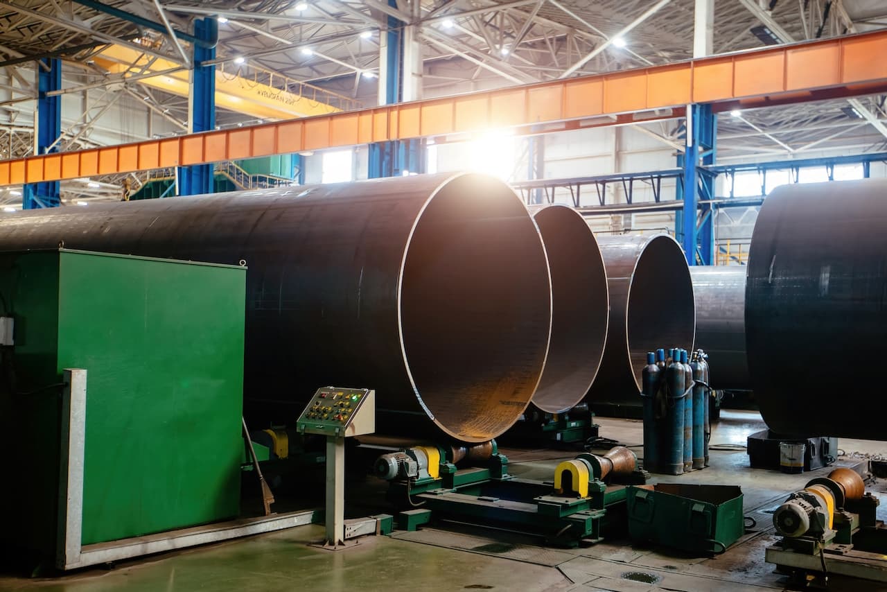Tubos de gran diámetro en un entorno industrial con una máquina de control y cilindros de gas.