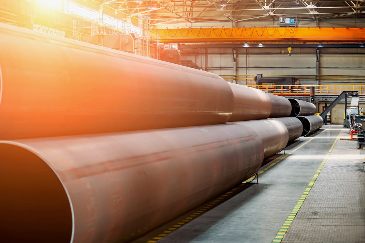 Tuberías grandes de acero almacenadas en un ambiente industrial con buena iluminación.